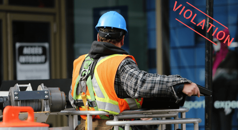 Man in reflective vest, hardhat, and fall protection harness